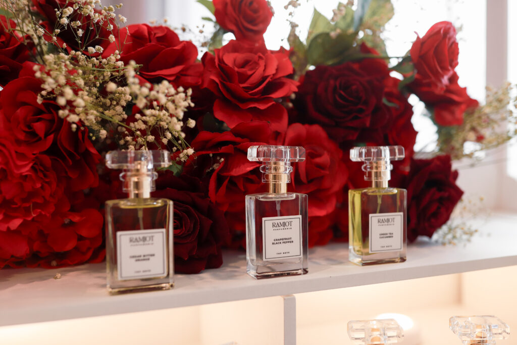 Custom Ramjot Parfumerie cart at Ma Chérie bridal shower in Calgary by Kinn Studios, with scalloped canopy, red rose garland and personalized signature perfume bottles